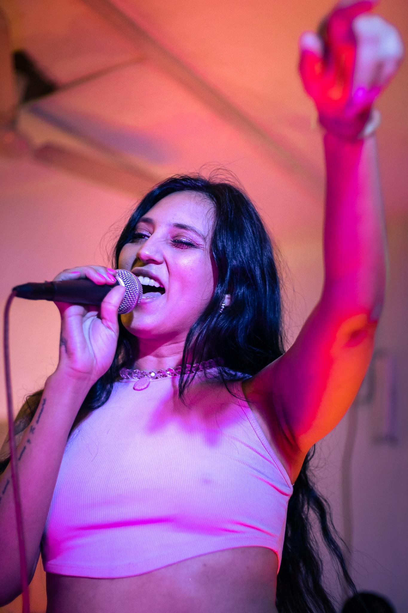 Dynamic live performance featuring a female singer energetically singing into a microphone.